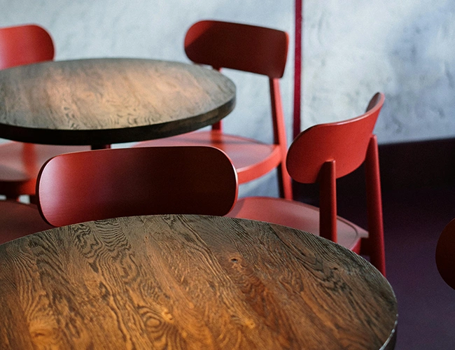 Vue de l'intérieur de Bakery Bliss Café, avec des tables en bois brut foncé et des chaises rouge basque, dans une ambiance conviviale et moderne.
